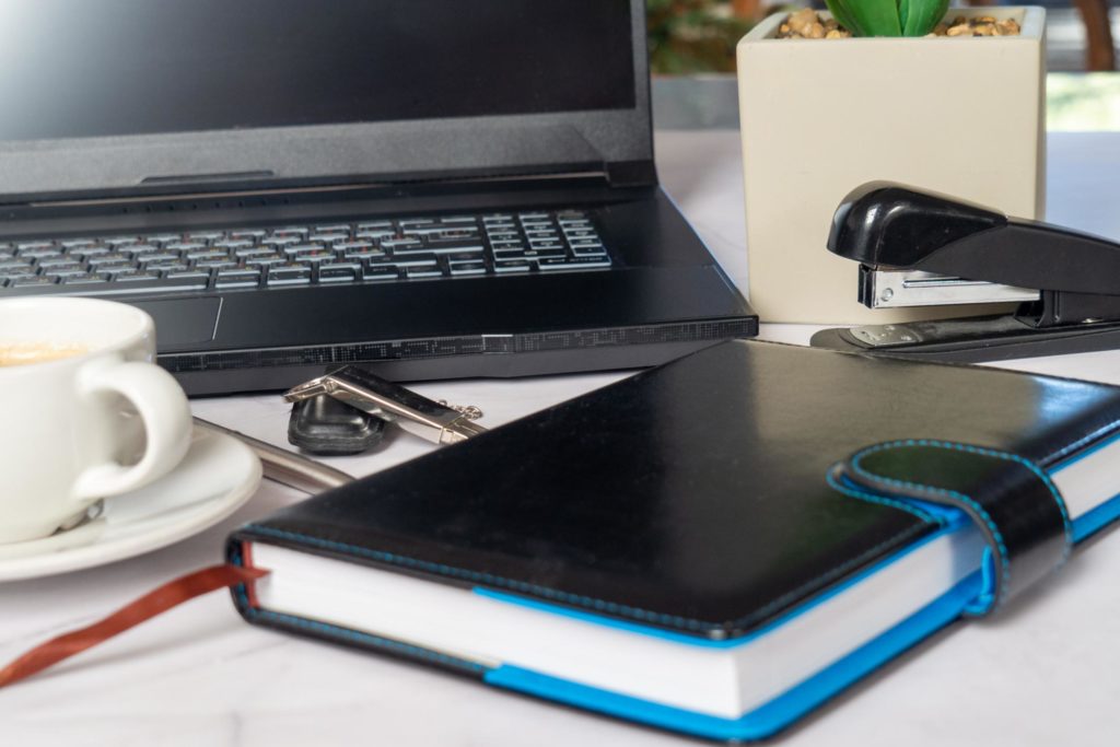 Stratégie de planification d’un sommet virtuel sur un bureau minimaliste avec ordinateur portable, carnet de notes et tasse de café